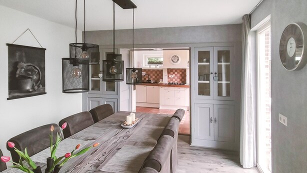 A dining area with a long table, chairs, and a vase with flowers. There is a kitchen visible through an open door. - Pet friendly home in Zeewolde with WiFi (Zeewolde)