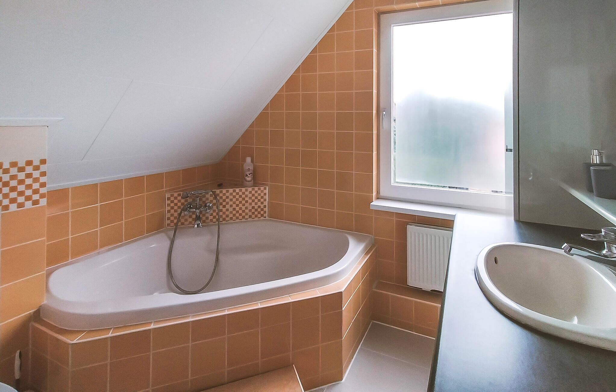A bathroom with a freestanding bathtub, a window, and a sink.