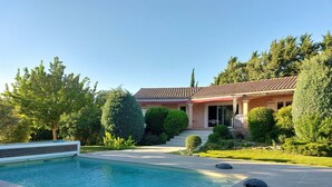 Ein Wohnhaus mit Schwimmbad, einer überdachten Terrasse und einem gepflegten Garten.