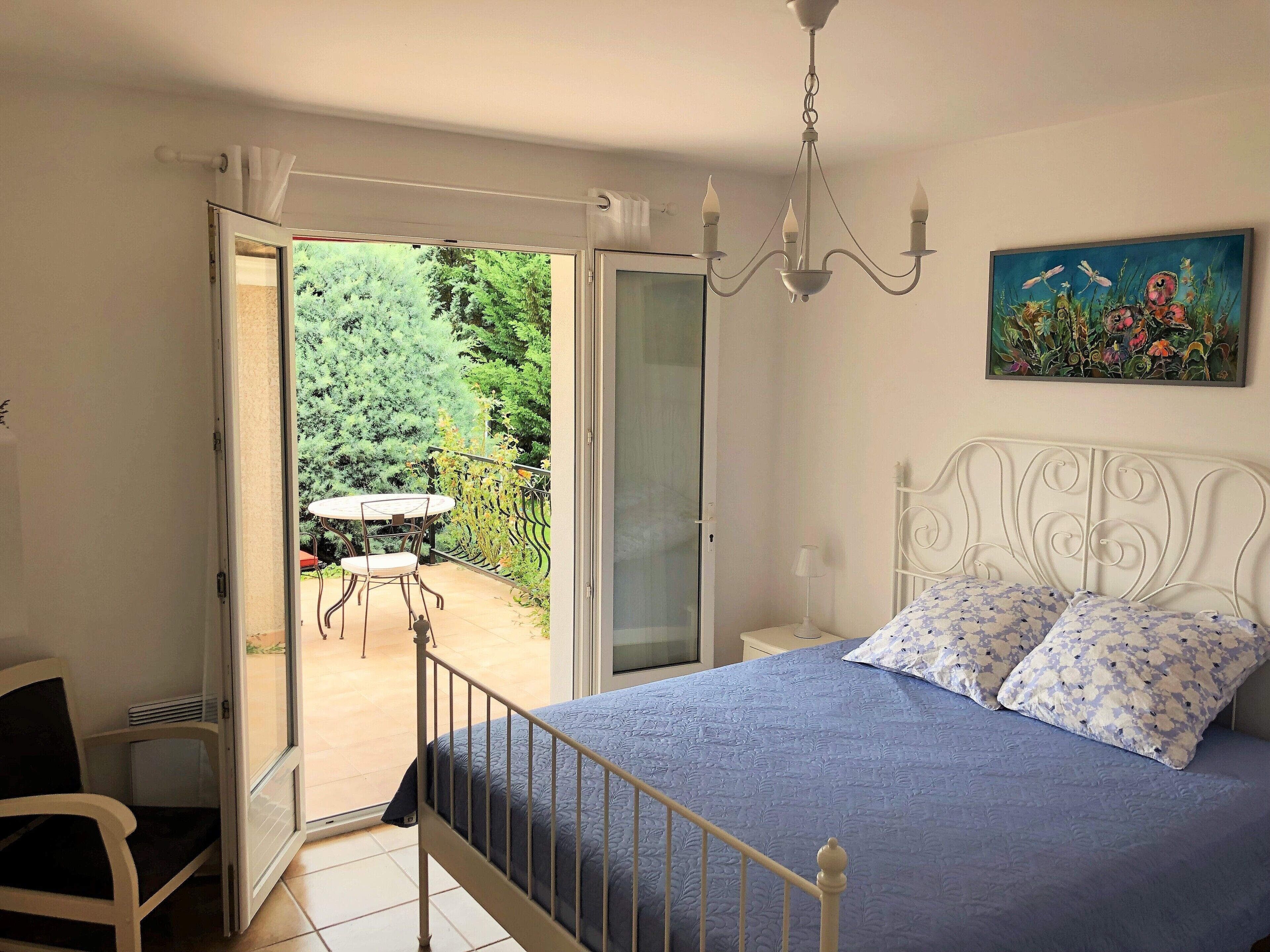 Une chambre avec un lit, une chaise, une table et un balcon donnant sur un paysage verdoyant.
