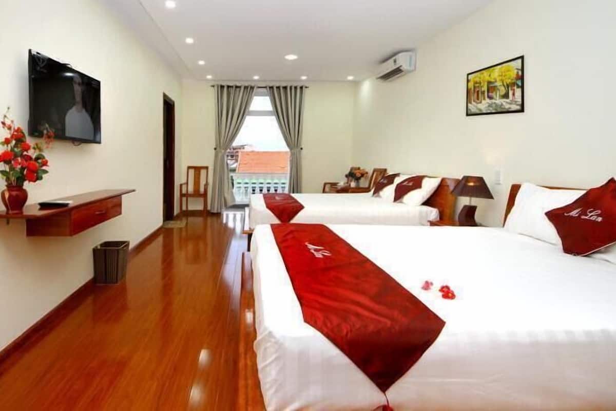 A hotel room with two beds, a TV, a painting, and a view of the outside.