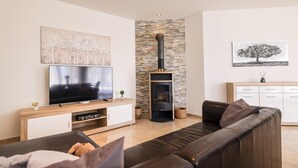 A modern living room with a flat-screen TV, a stone fireplace, a sofa, and artwork on the walls. - Beach front home in Vrsi (Vrsi)