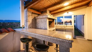 An outdoor kitchen with a stone oven, granite countertop, and two black bowls. - Beach front home in Vrsi (Vrsi)