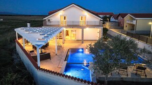 A two-story house with a swimming pool, outdoor seating, and a covered patio area. - Beach front home in Vrsi (Vrsi)