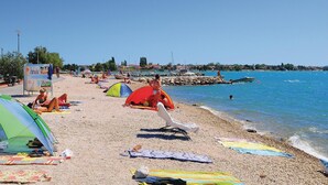 A beach with tents, people sunbathing, and boats in the water. - Beach front home in Vrsi (Vrsi)