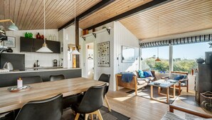 A modern kitchen with wooden beams, a dining area with a large table and chairs, and a cozy seating area with a sofa and cushions. - Nice home in Hvide Sande with WiFi (Hvide Sande)