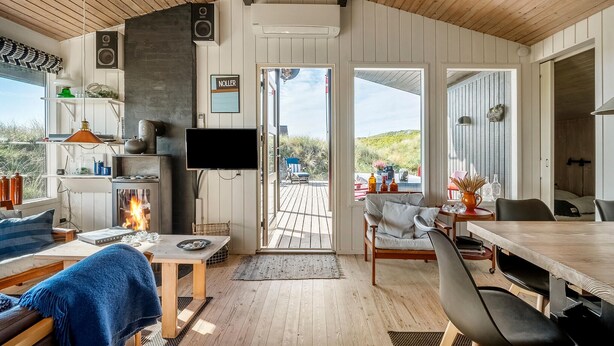 A cozy cabin interior with a fireplace, a TV, and a dining area. - Nice home in Hvide Sande with WiFi (Hvide Sande)