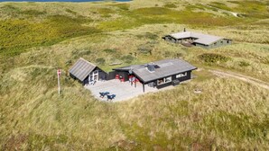 A modern, two-story building with a flat roof, situated on a grassy hill with a view of the sea. - Nice home in Hvide Sande with WiFi (Hvide Sande)