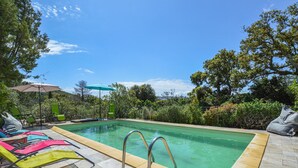 A rectangular swimming pool with a tiled edge, surrounded by a patio area with green lounge chairs and a single umbrella. - Beautiful home in Porto Vecchio (Porto Vecchio)