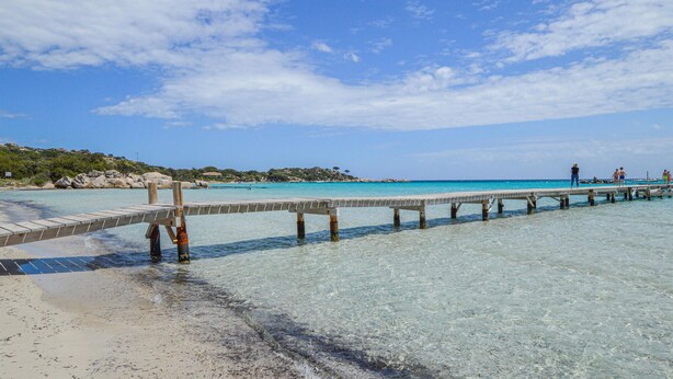 A pier extending into clear turquoise waters with a sandy beach and rocky hills in the background. - Beautiful home in Porto Vecchio (Porto Vecchio)