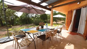 An outdoor patio with a table and chairs, surrounded by umbrellas and a view of the garden. - Beautiful home in Porto Vecchio (Porto Vecchio)