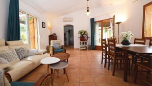 A living room with a sofa, two chairs, a small table, and a dining area with a table and chairs. - Beautiful home in Porto Vecchio (Porto Vecchio)