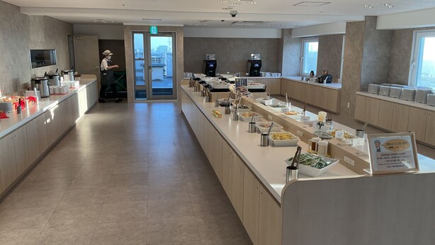 A modern breakfast buffet with a variety of food options, a coffee station, and a view of the city through the glass doors. - Toyoko Inn Nishi Funabashi Baraki Inter (Ichikawa)