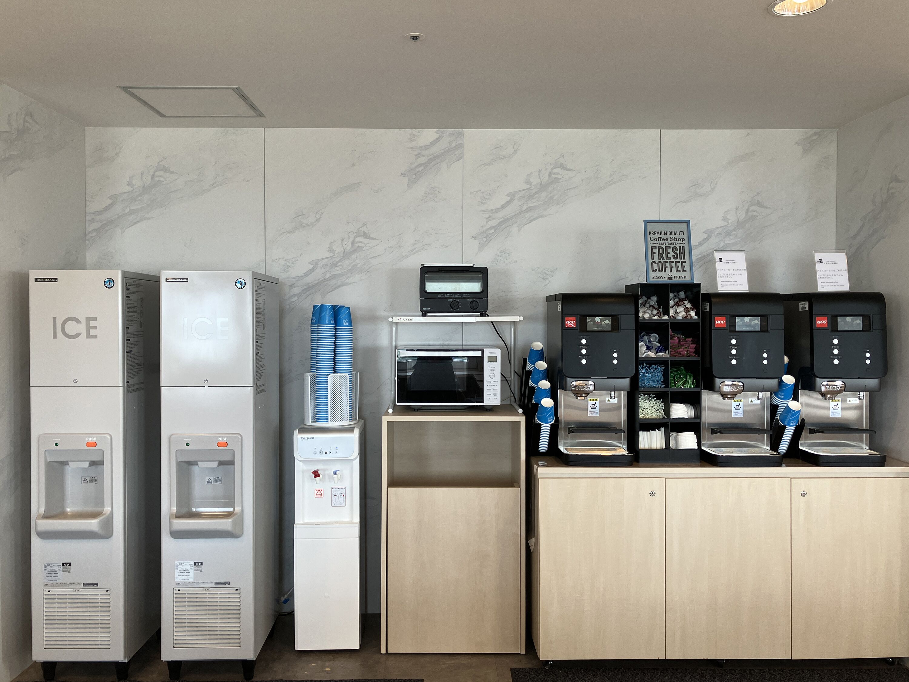 A self-service beverage station with ice dispensers, a microwave, and coffee machines.