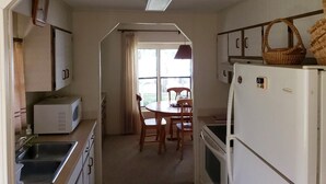 A compact kitchen with a microwave, sink, and refrigerator. There is a dining area with a table and chairs. - Waterfront property! (Welaka)