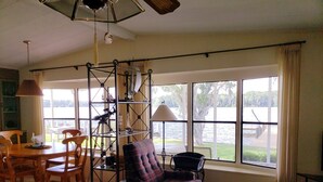A room with a large window, a telescope, a dining table with chairs, and a plaid armchair. - Waterfront property! (Welaka)