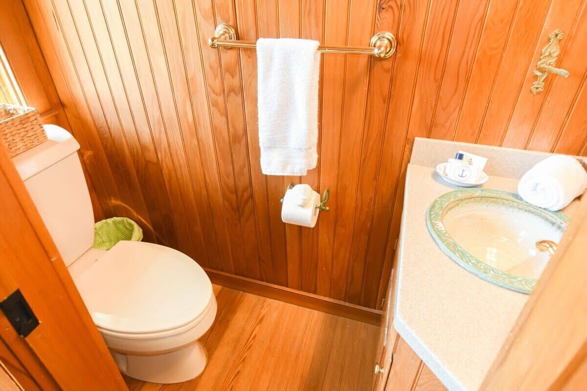 A compact bathroom with a wooden vanity, a toilet, and a towel rack.