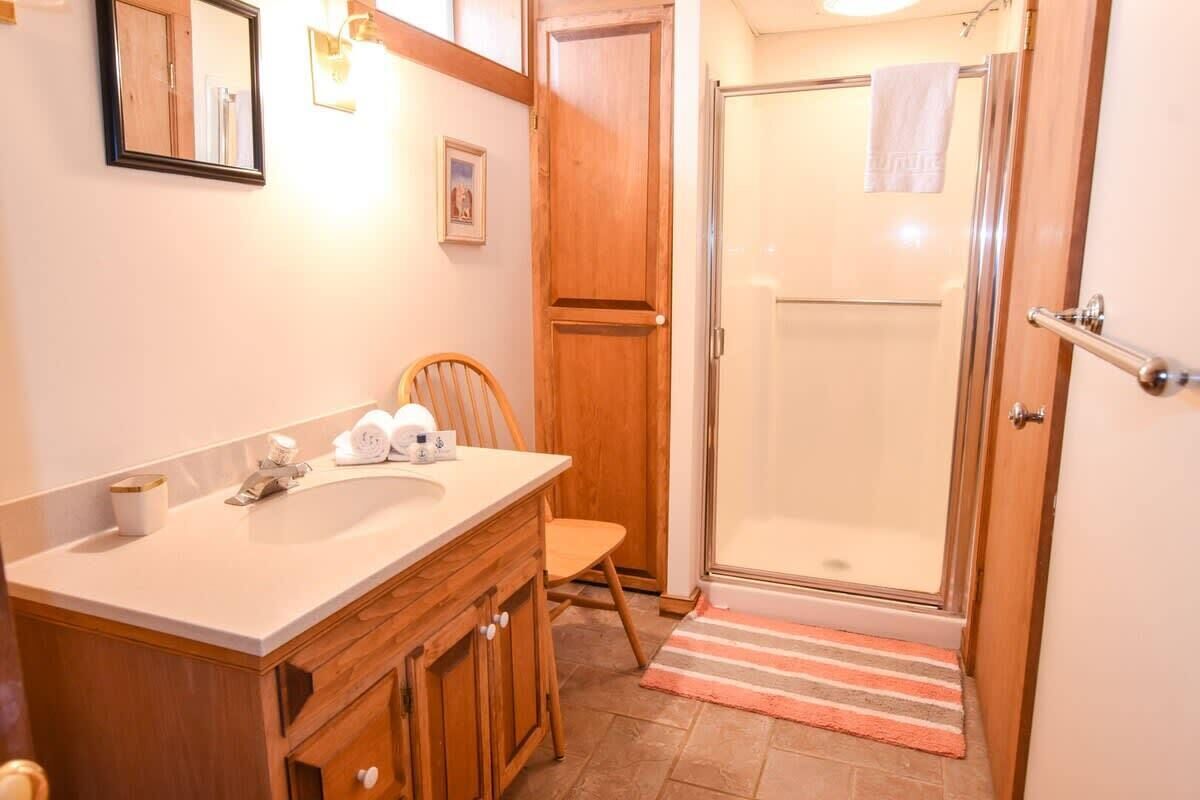 A bathroom with a wooden vanity, a shower, and a towel rack.