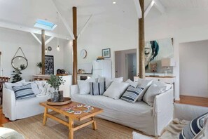 A modern living room with a white sofa, a wooden coffee table, and a hanging light fixture.