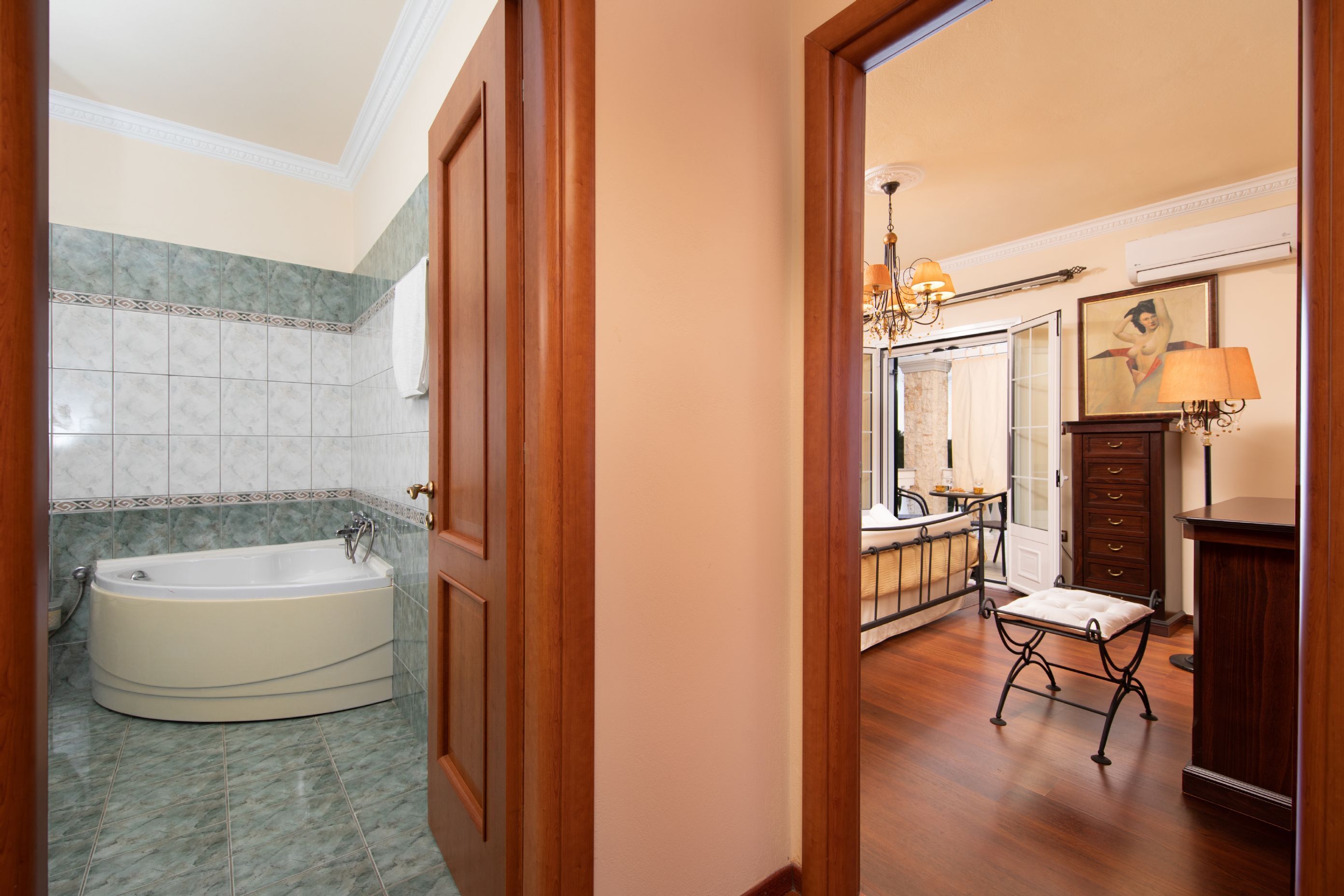 Un baño con una bañera grande, un tocador con espejo y un banco de madera.