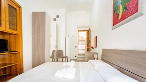 Een hotelkamer met een groot bed, een houten garderobe, een bureau en een stoel.