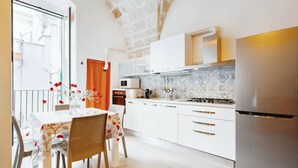 Een moderne keuken met witte kastjes, een roestvrijstalen koelkast en een betegelde achterwand.