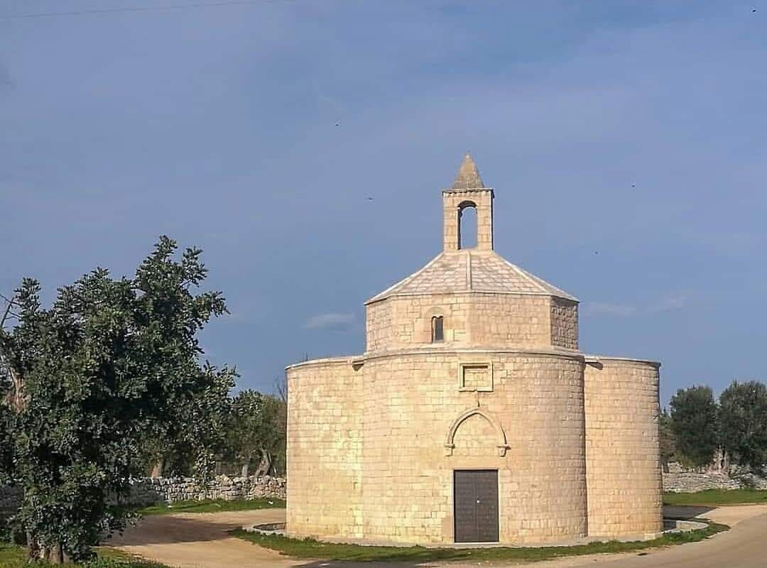 Un bâtiment circulaire en pierre, doté d’un clocher, d’une porte et d’une petite fenêtre.