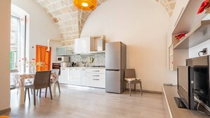 Een moderne keuken met witte kasten, een koelkast en een eethoek met een tafel en stoelen.