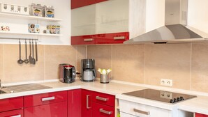 Una cocina moderna con armarios rojos y blancos, horno empotrado y cafetera.