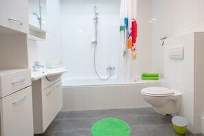 Moderni kylpyhuone, jossa on kylpyamme, wc ja pesuallas.
