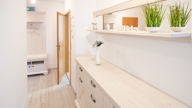 Un baño moderno con tocador de madera, un espejo y una estantería con plantas y artículos de aseo.