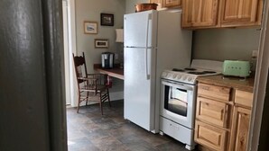 Cocina compacta con refrigerador, estufa y armarios de madera.
