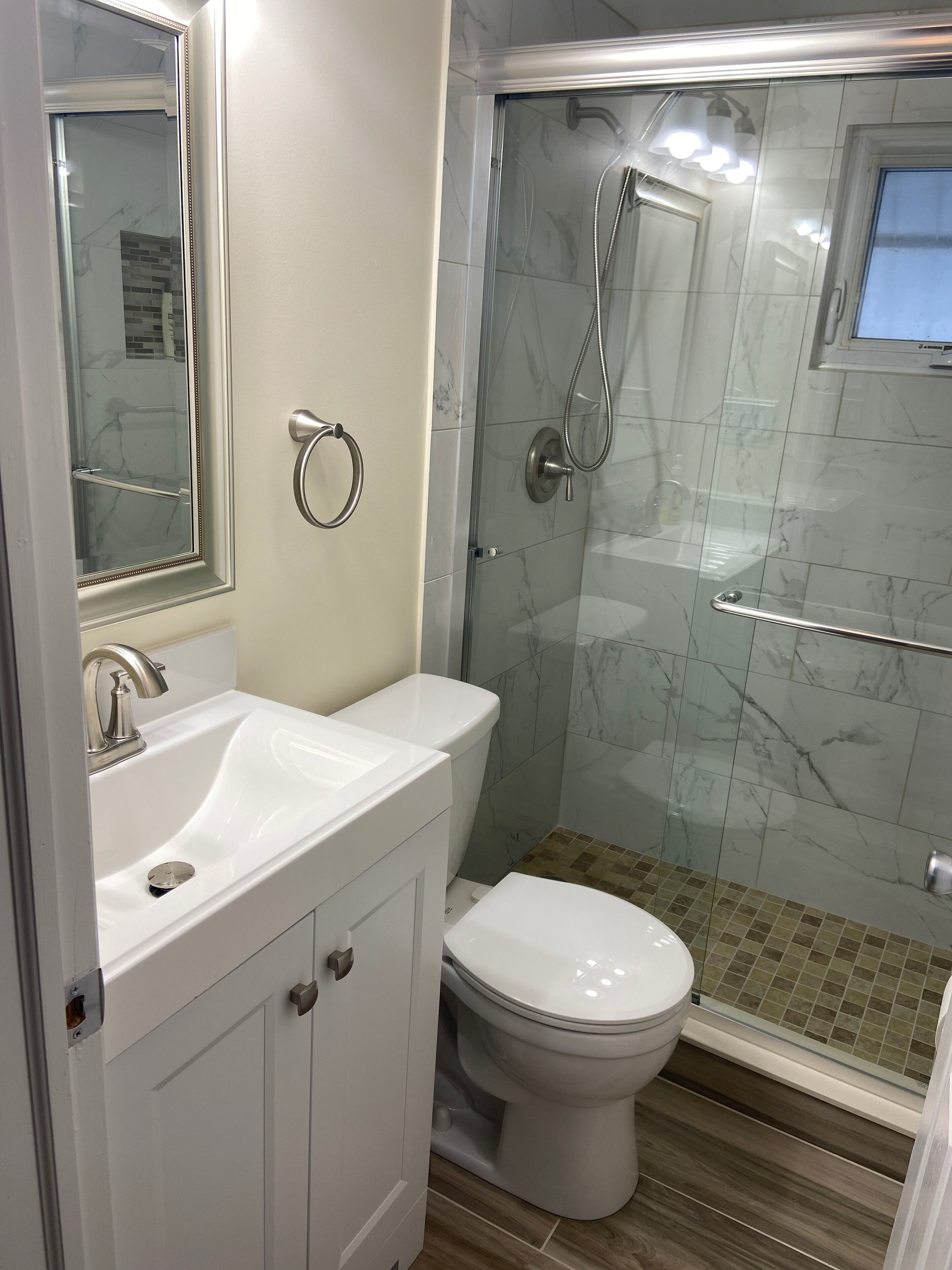 A bathroom with a white sink, toilet, and glass shower enclosure.