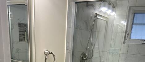A bathroom with a white sink, toilet, and glass shower enclosure.