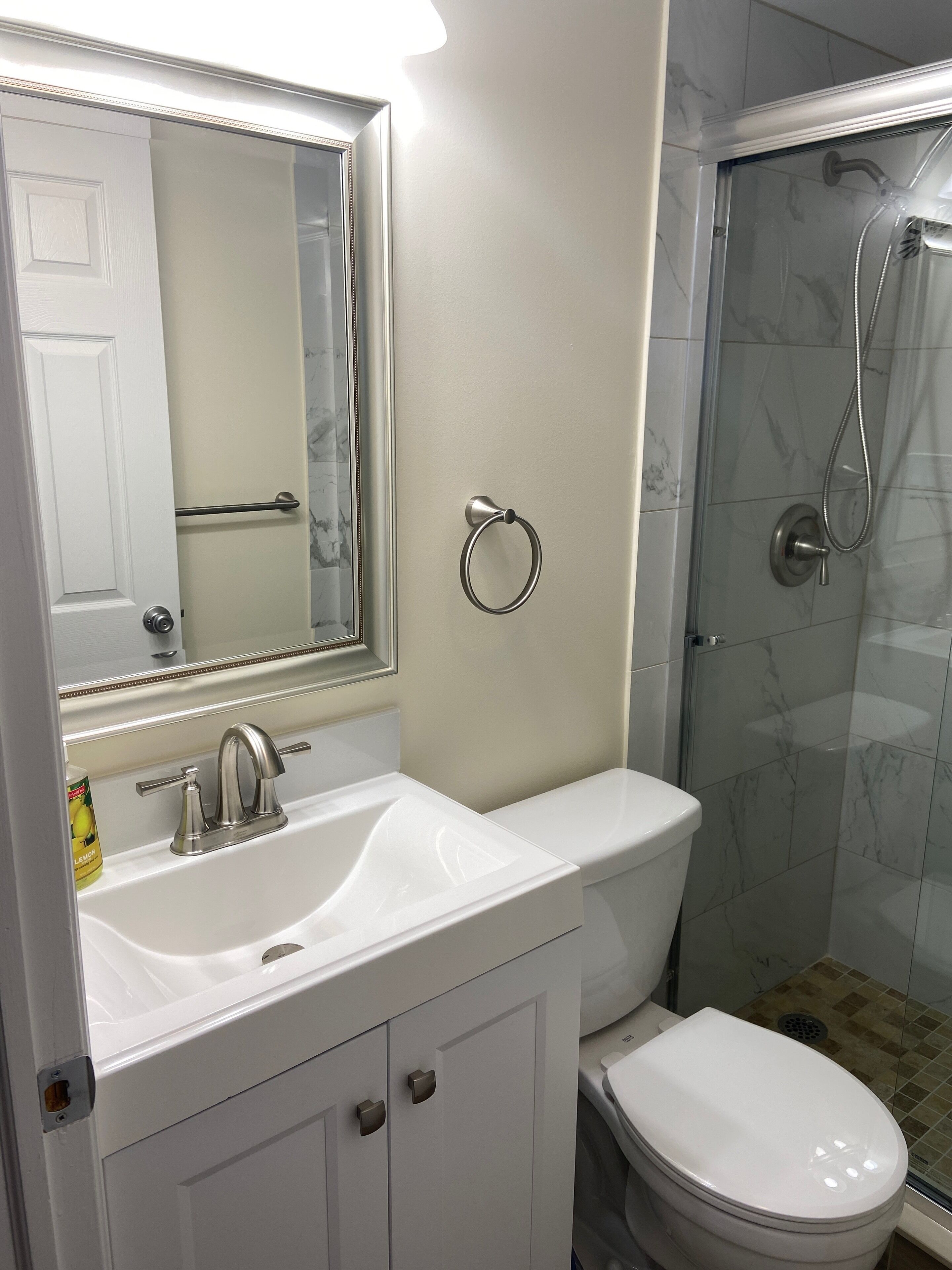 A bathroom with a white sink, mirror, and toilet, and a glass-enclosed shower area.