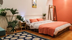 Ein Schlafzimmer mit einem Bett, zwei Nachttischen, einem Hängesessel und Topfpflanzen.