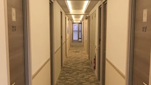 Een hotelgang met vloerbedekking, deuren genummerd 218 en 217, en een brandblusser aan de muur.