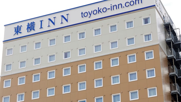 Een meerhoog gebouw met een bord waarop 'TOYOKO INN' staat en de website 'toyoko-inn.com'.