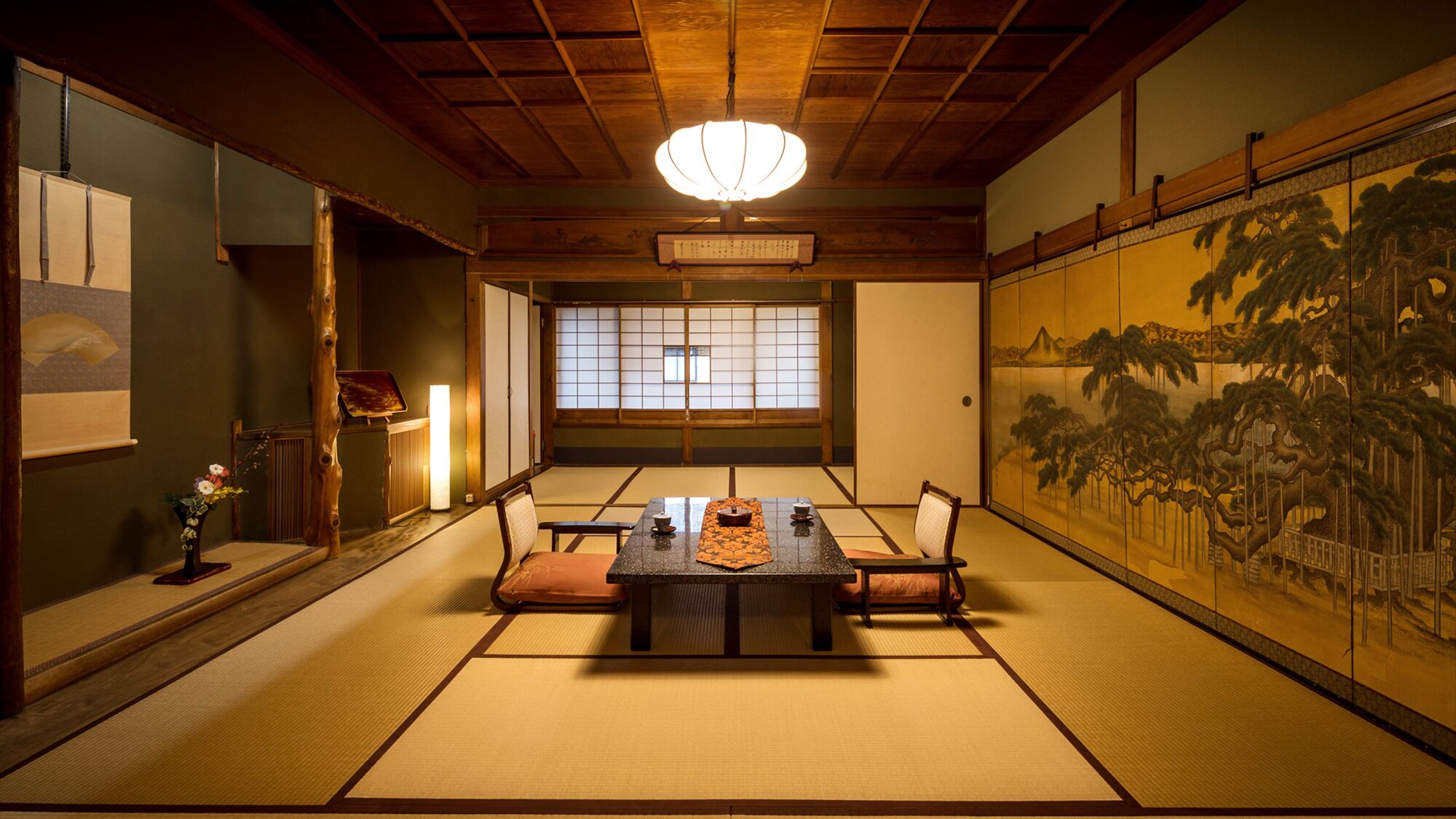 Um quarto japonês tradicional com tatames, uma mesa baixa com almofadas, um painel shoji e um pergaminho pendurado.