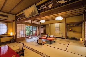 Una habitación japonesa tradicional con suelo de tatami, una mesa baja con cojines y puertas correderas.