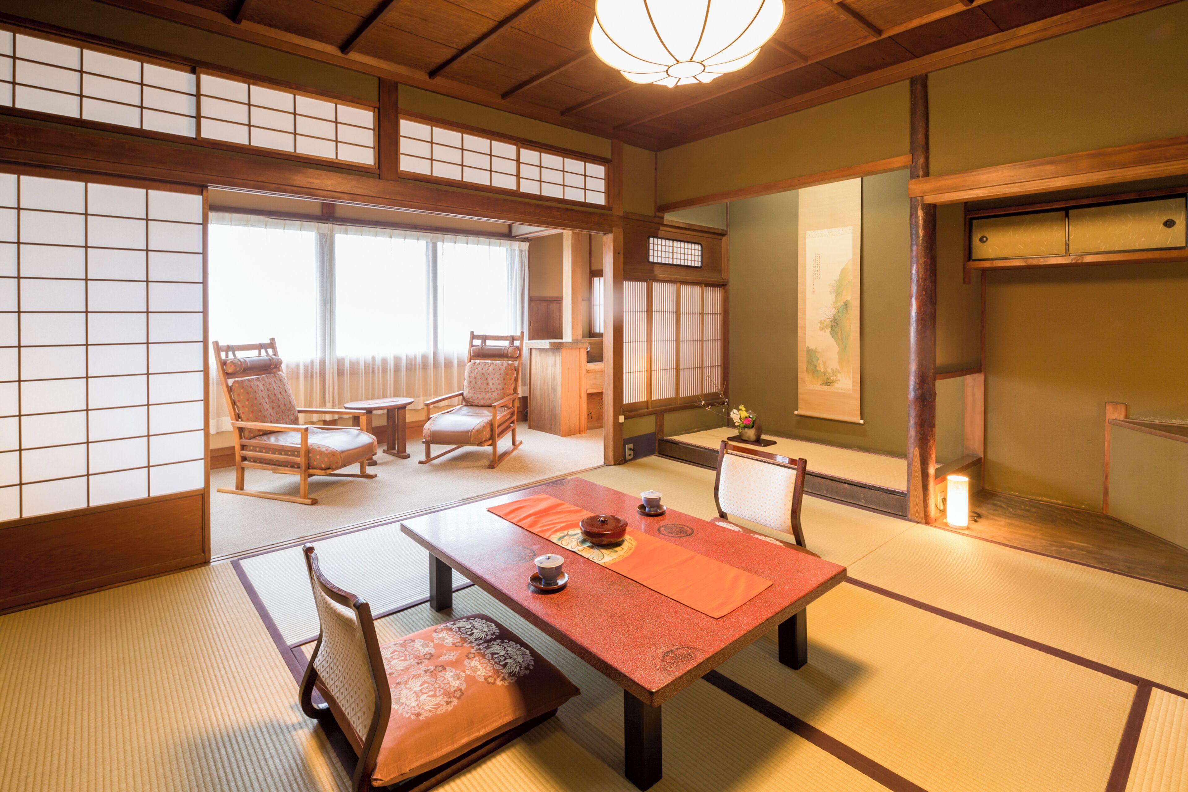 A traditional Japanese room with tatami flooring, a low table with a tea set, and sliding doors.