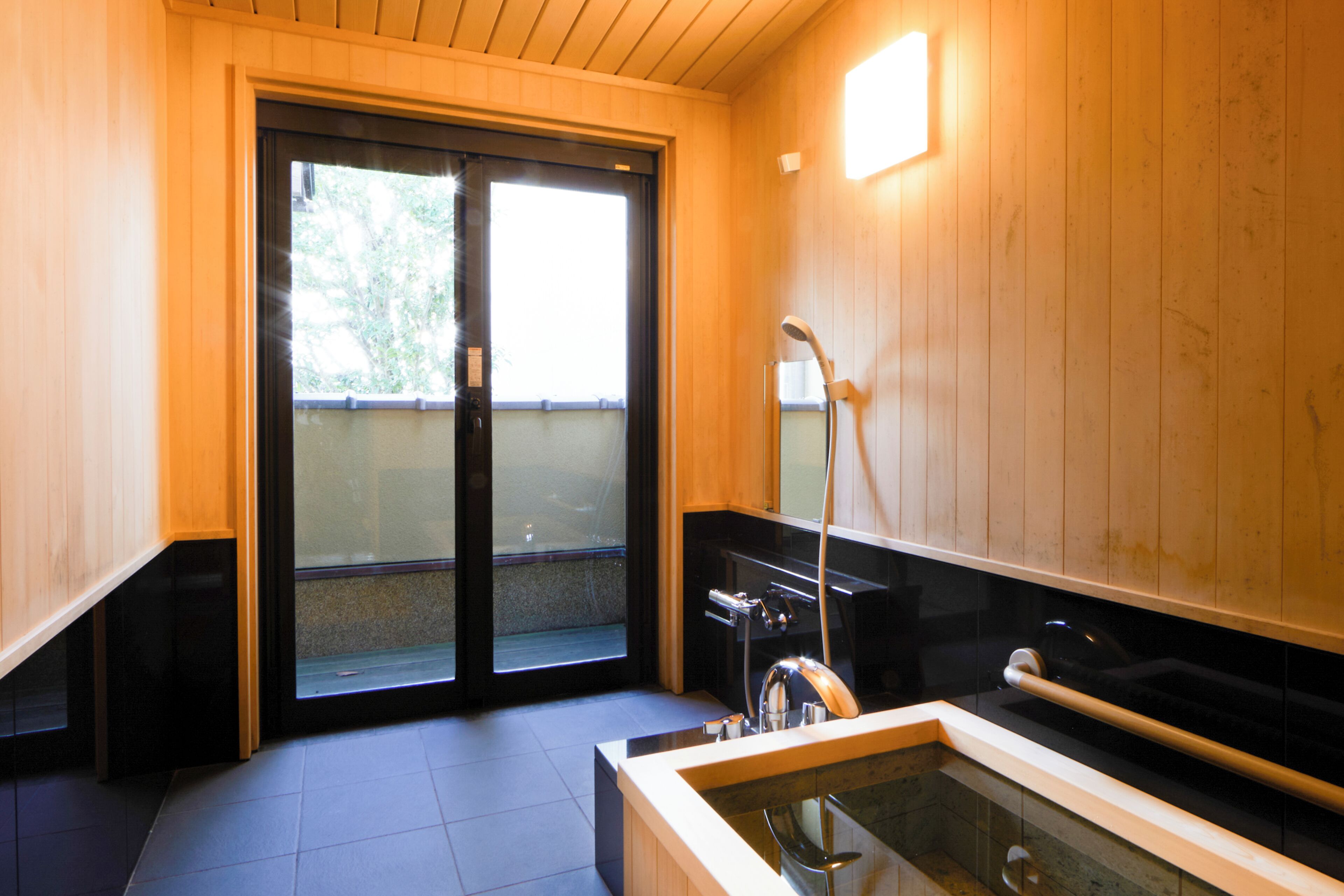 Ein modernes Badezimmer mit Glasdusche, einer Badewanne und Holzvertäfelung.
