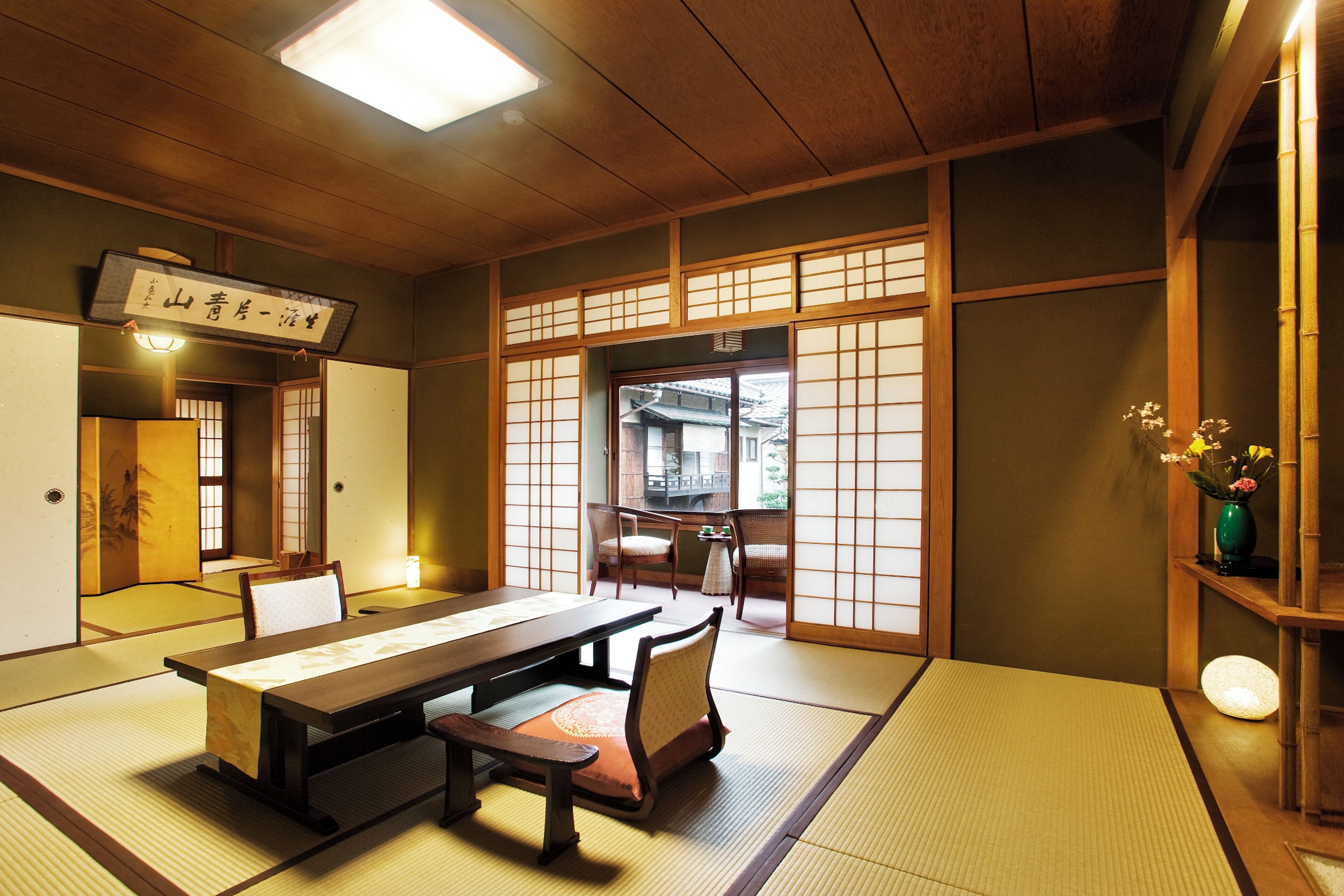 A traditional Japanese room with tatami flooring, a low table, and sliding doors.