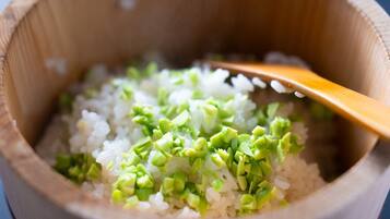 A wooden bowl containing rice and chopped green vegetables.