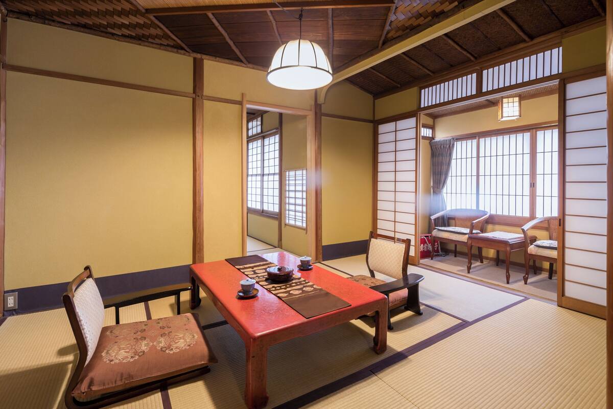 Um quarto japonês tradicional com tatames, uma mesa de madeira baixa e portas deslizantes.