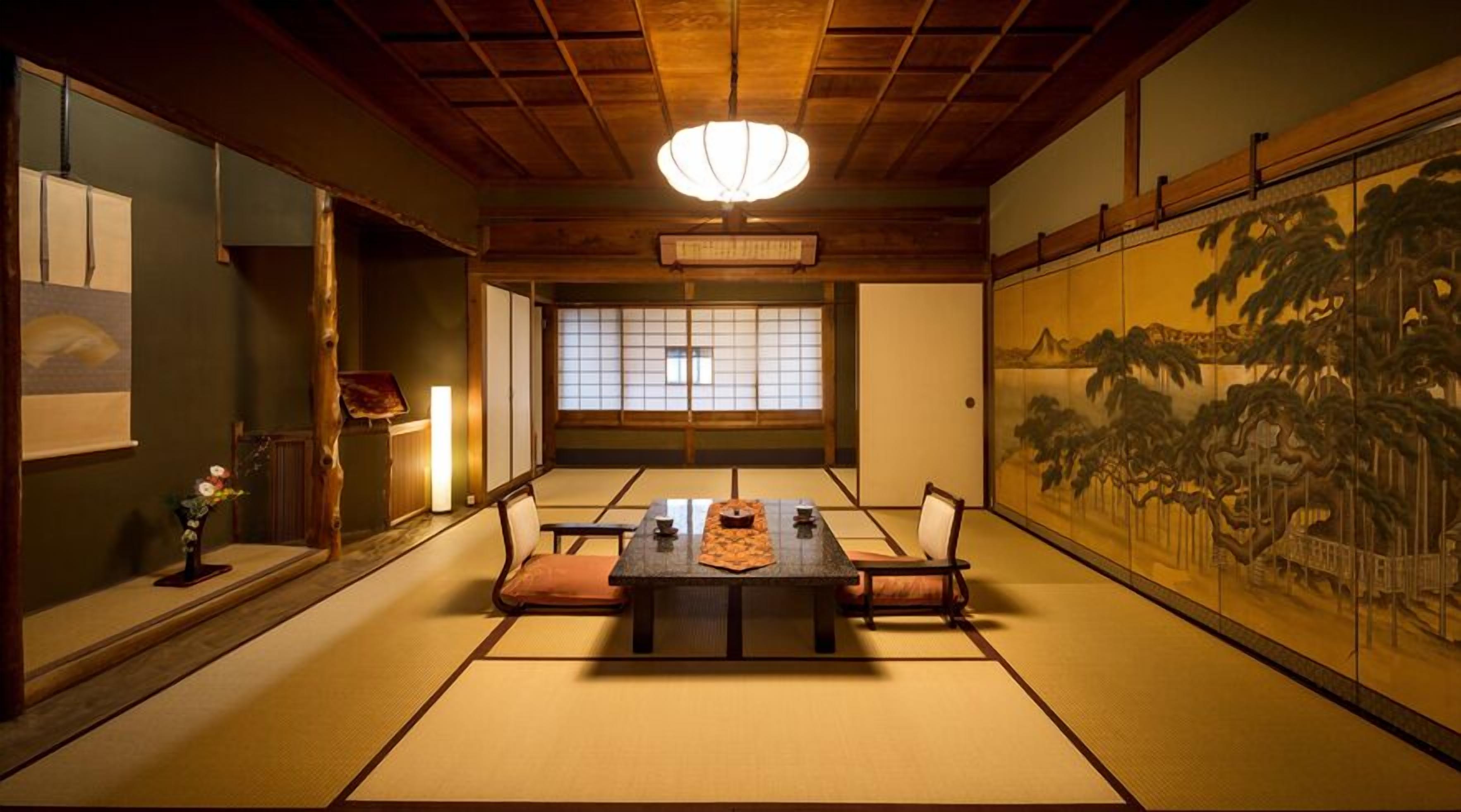 Um quarto japonês tradicional com tatames, uma mesa baixa e um shoji com pintura de paisagem.