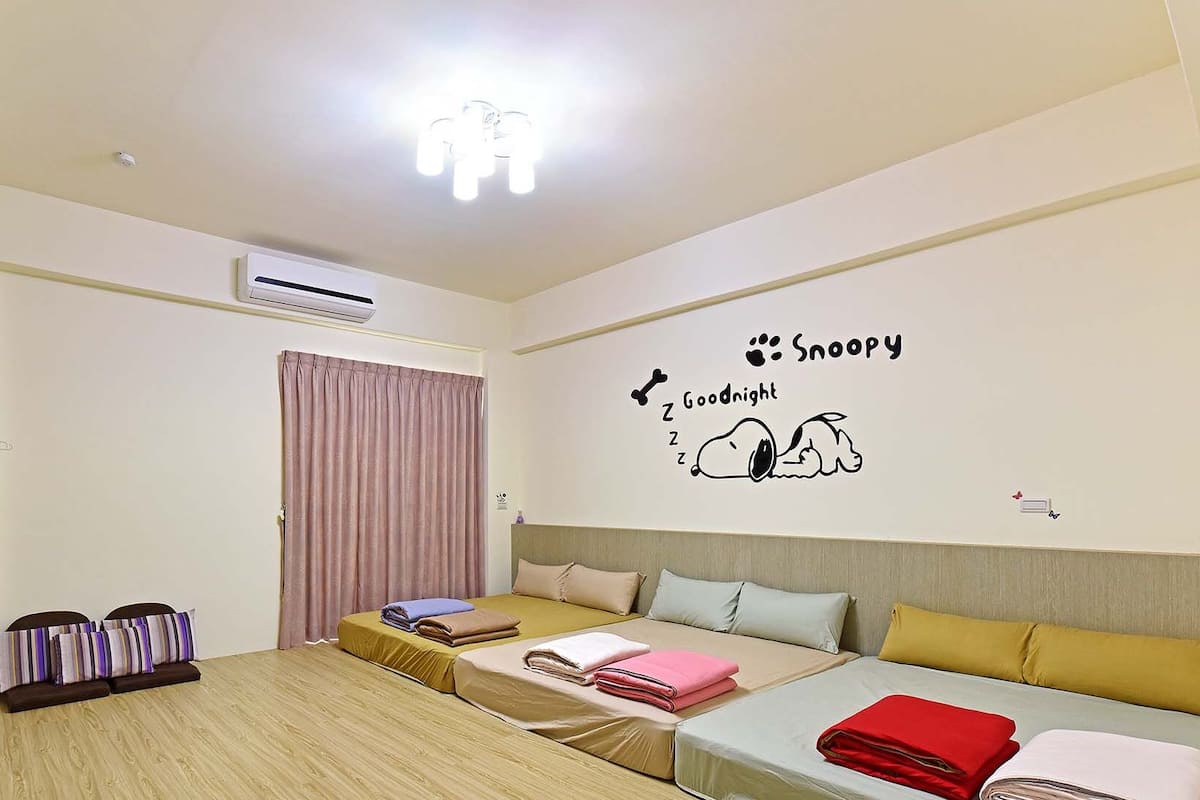 Ein Hotelzimmer mit Bett, einer Couch, einem Fernseher, einer Klimaanlage und einer Wanddekoration.