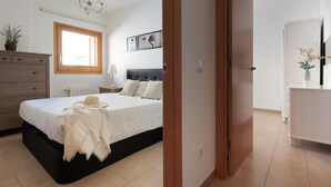 A bedroom with a bed, bedside tables, a dresser, a window, and a door leading to another room. - MEDITERRANEAN APARTMENT 3 minutes TO THE BEACH 2 (Tossa de Mar)