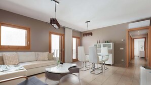 A modern living room with a sofa, a round coffee table, and a dining area with chairs. - MEDITERRANEAN APARTMENT 3 minutes TO THE BEACH 2 (Tossa de Mar)
