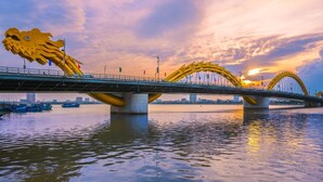 A bridge with large dragon sculptures and a city skyline in the background. - S HOTEL BEACH DA NANG (Da Nang)